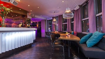 A modern restaurant with a bar area, seating, and a large window with curtains.