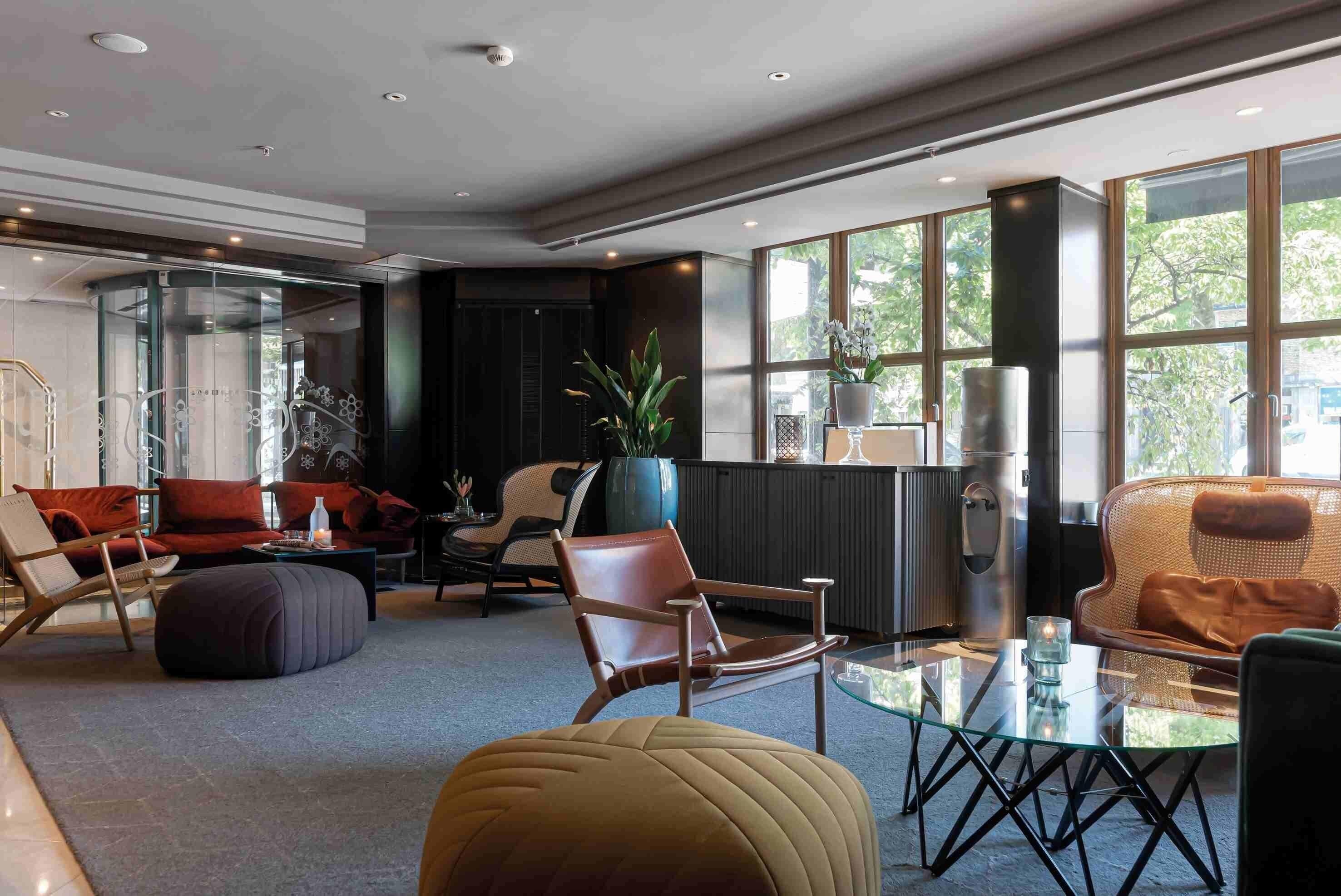 A modern living room with a glass coffee table, leather sofas, and a large window offering a view of the outdoors.
