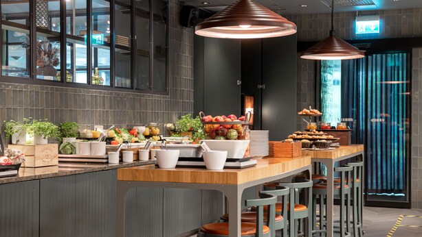 Una cocina moderna con una isla central, taburetes de bar e iluminación colgante.