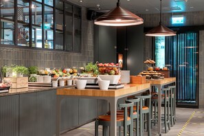 A modern kitchen with a central island, bar stools, and pendant lighting. - Elite Park Avenue Hotel (Gothenburg)