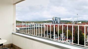 Un balcone con vista sulla città, tra cui edifici e una ruota panoramica.
