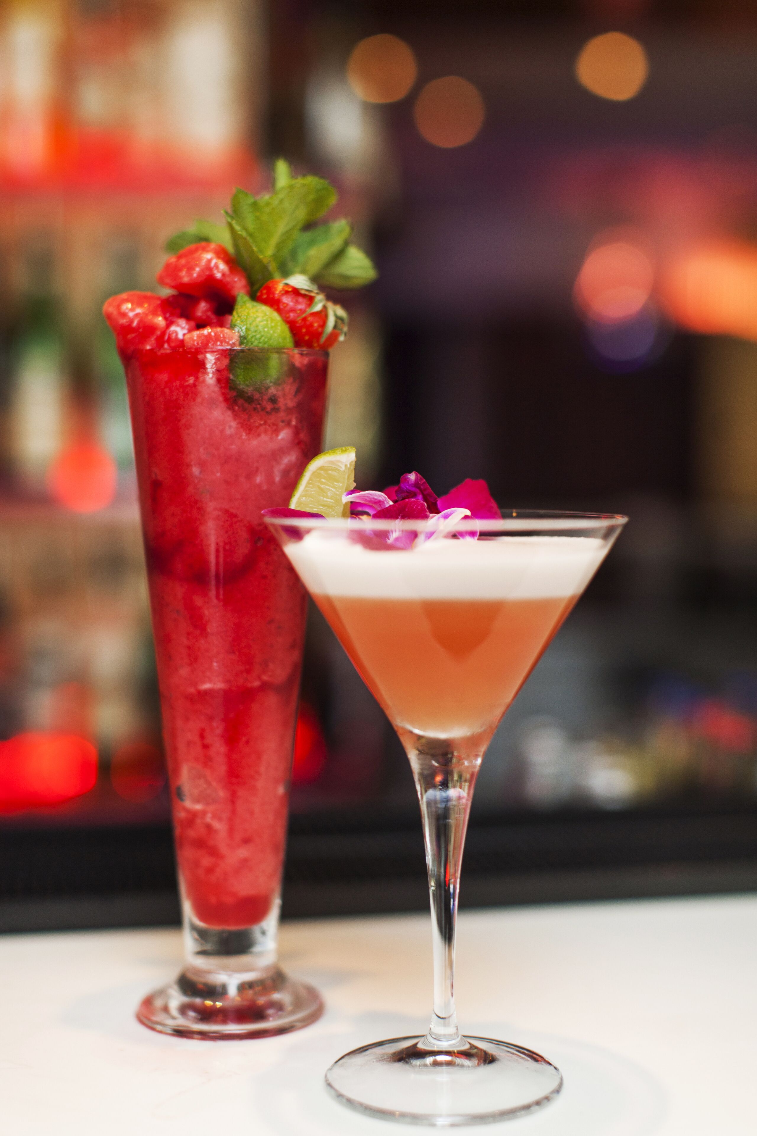 Deux cocktails, l’un servi dans un grand verre et l’autre dans un verre à martini, décorés de garnitures.