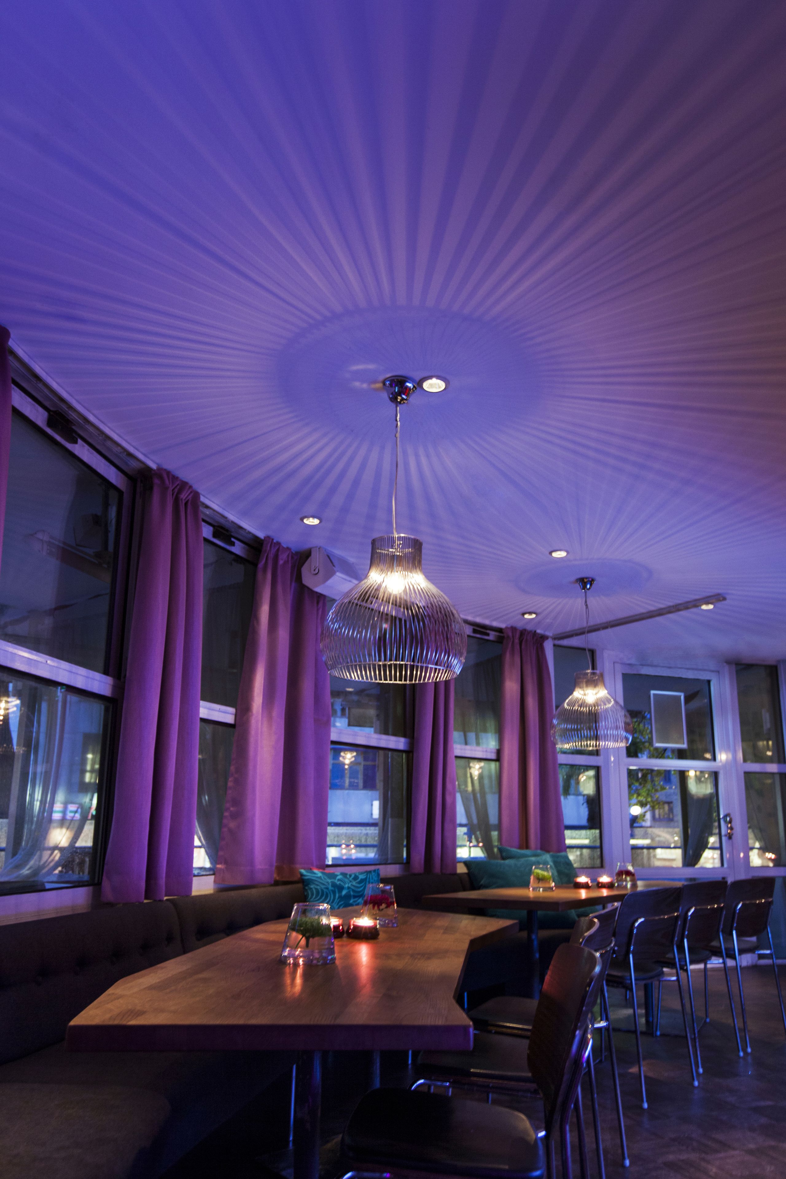 A modern dining area with a large table, multiple chairs, and pendant lighting.