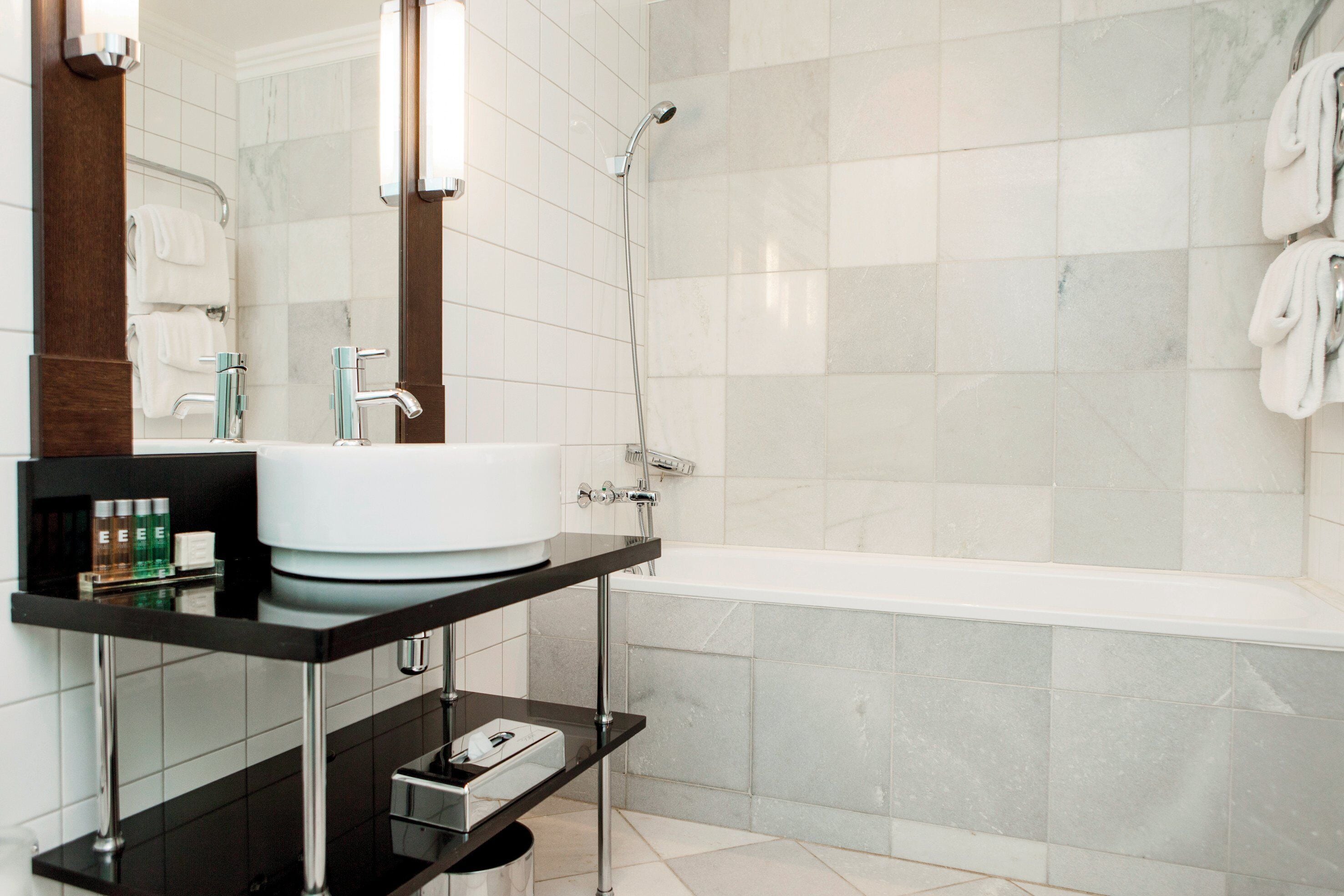 A modern bathroom with a white sink, a mirror, and a shower.