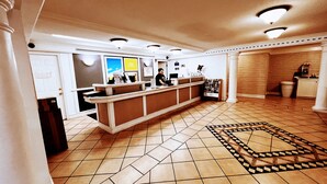 A reception area with a reception desk, a tiled floor, and a patterned rug. - Sulphur Extended Stay (Sulphur)