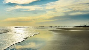 A beach with a calm sea, a clear sky, and a row of utility poles on the right. - Sulphur Extended Stay (Sulphur)
