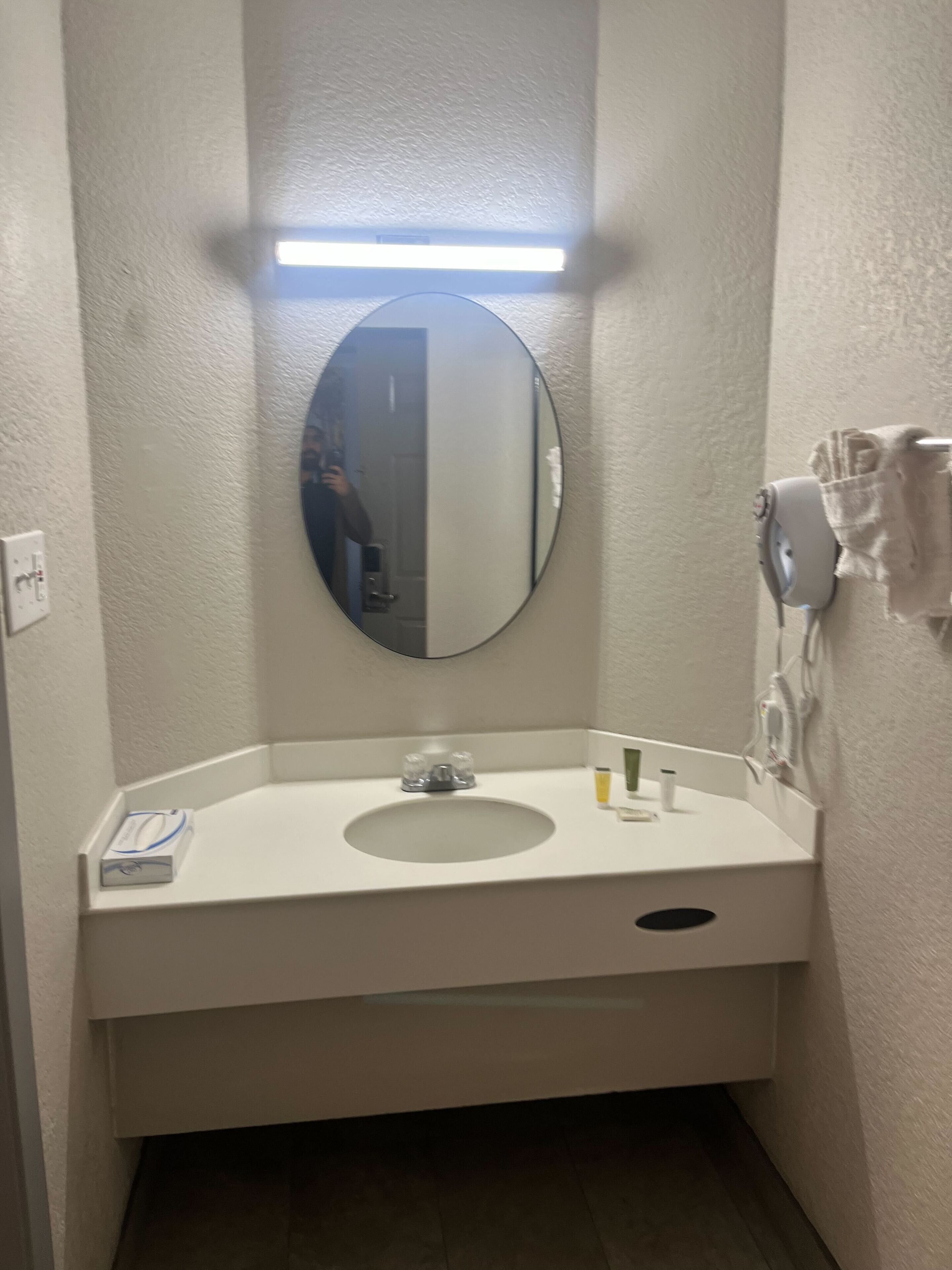 A small bathroom with a white sink, a round mirror, and a towel rack.
