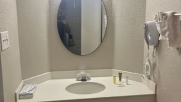 A small bathroom with a white sink, a round mirror, and a towel rack.