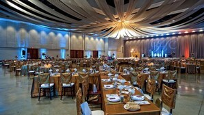 A large banquet hall with long tables set for a formal event, featuring a modern ceiling design and a stage at the far end. - Sulphur Extended Stay (Sulphur)