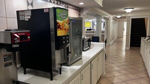 A kitchen with a refrigerator, microwave, and a juice dispenser. - Sulphur Extended Stay (Sulphur)