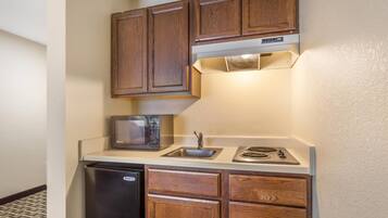A compact kitchen with wooden cabinets, a microwave, a sink, and a dishwasher.