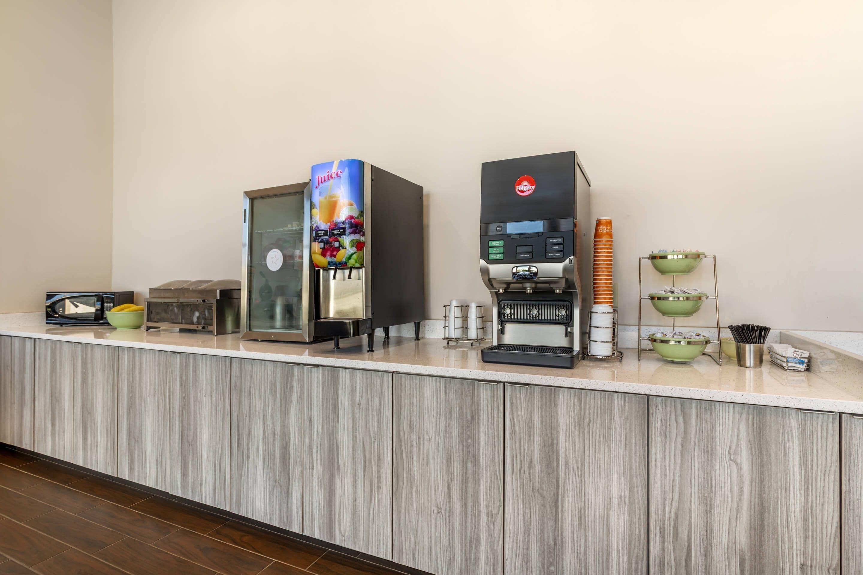 A self-service beverage station with a coffee machine and a juice dispenser.