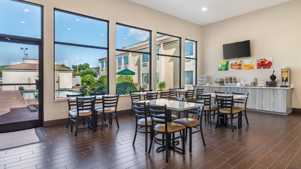 Un comedor amplio con ventanas grandes, vista a la piscina y una zona de cocina con televisor de pantalla plana y diversos servicios.