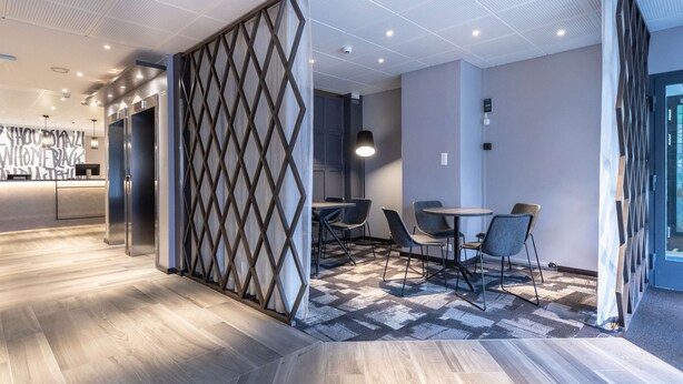 Un intérieur moderne avec un plancher en bois, un coin repas comprenant des chaises et une table, et un espace cuisine avec un comptoir et des chaises.