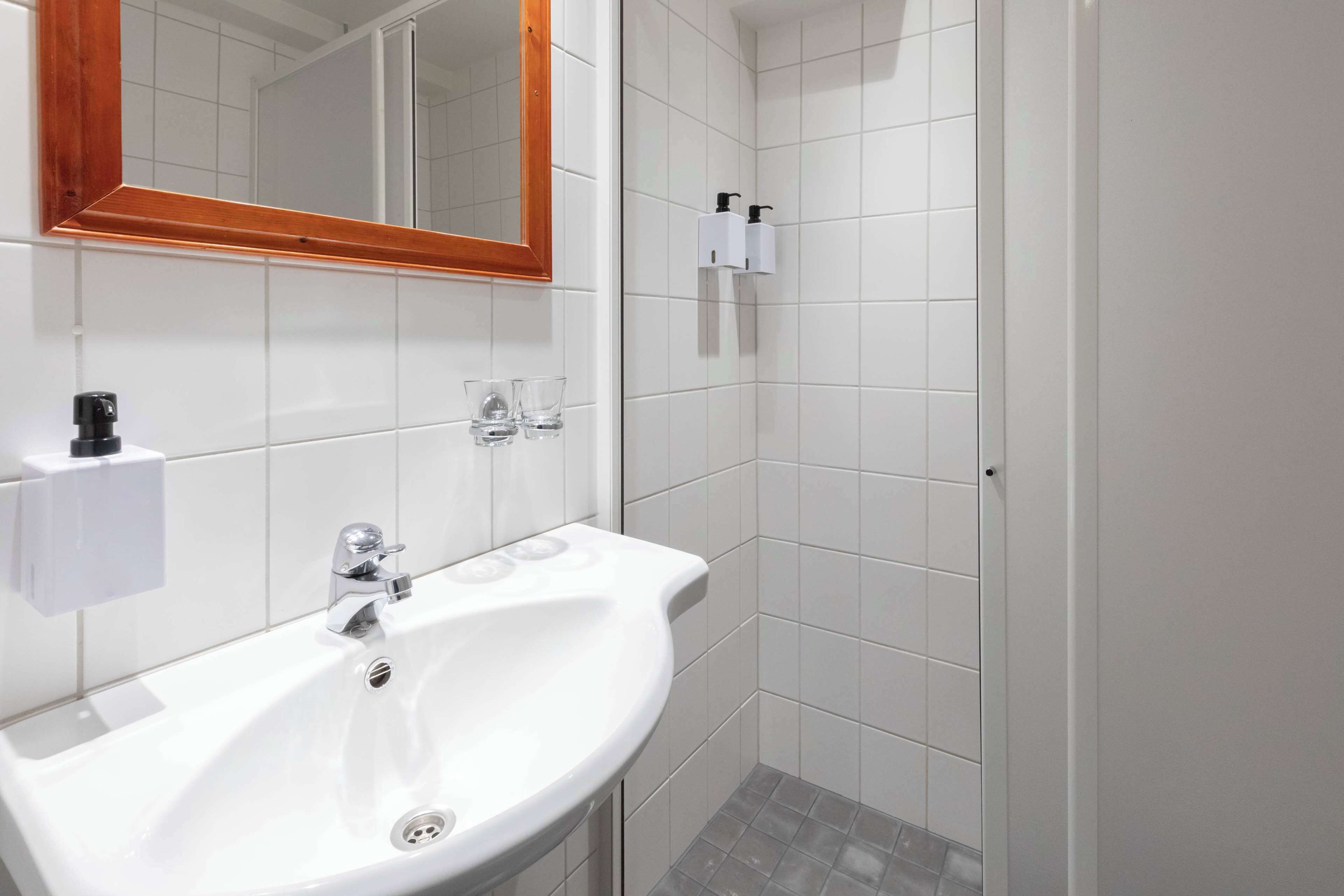 A bathroom with a white sink, mirror, and tiled walls.