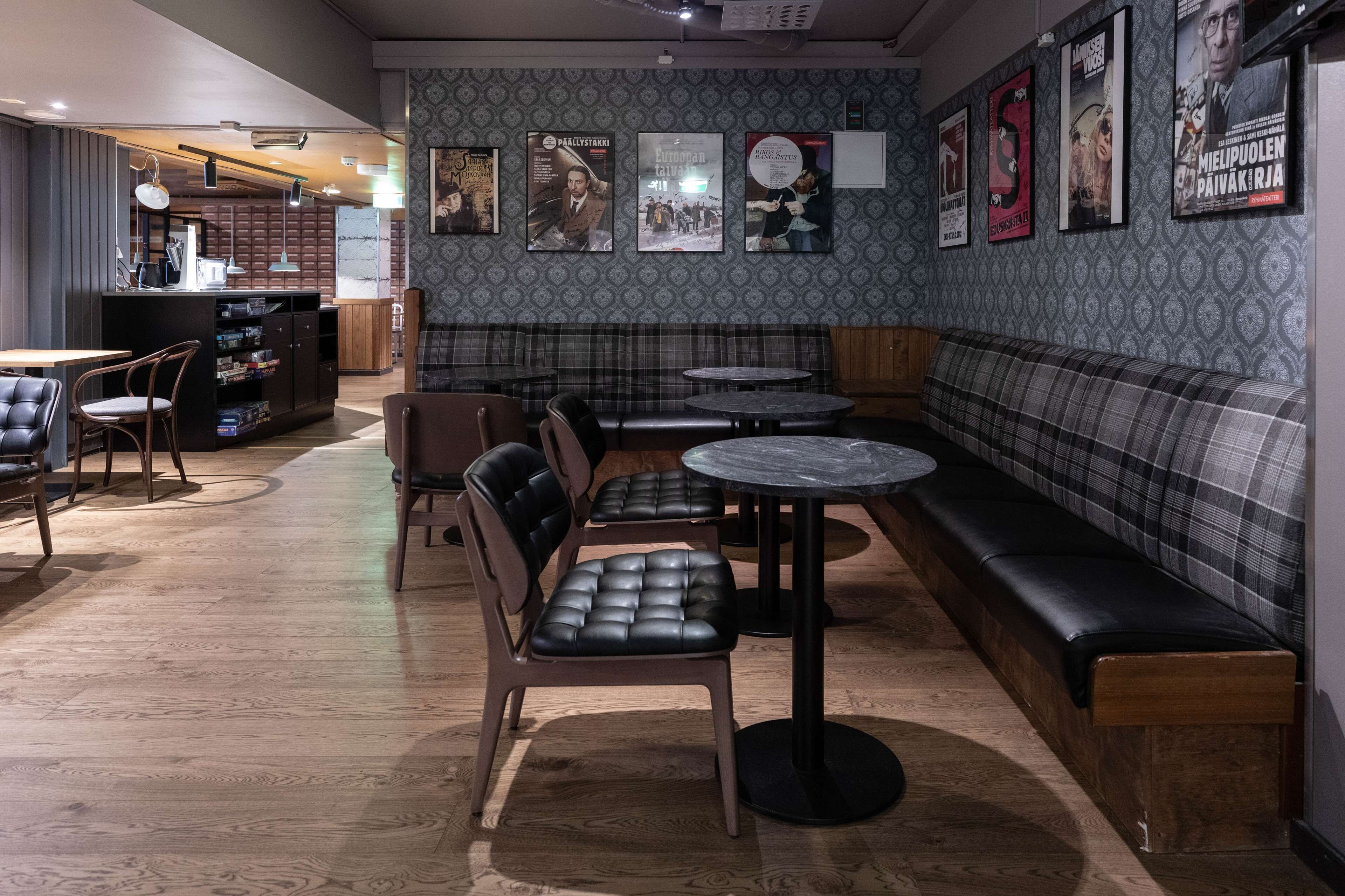 Un accogliente interno di un ristorante con un'area bar, posti a sedere e manifesti di film alle pareti.