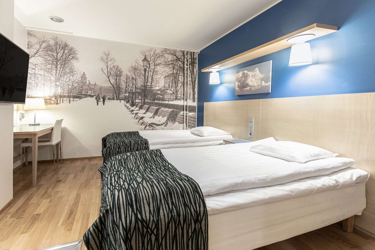 A hotel room with two beds, a desk, and a chair.