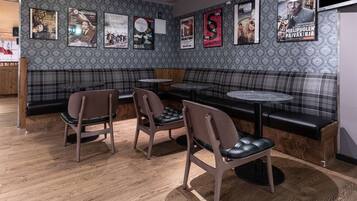 Un interior de restaurante con un muro estampado, una zona de estar con bancos y sillas, y un suelo de madera.