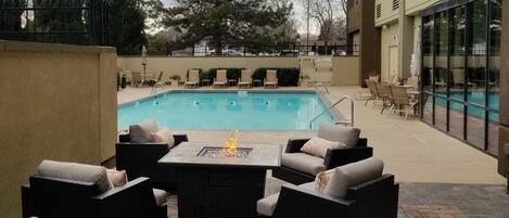 Un área de piscina al aire libre con sillones de descanso y una chimenea.