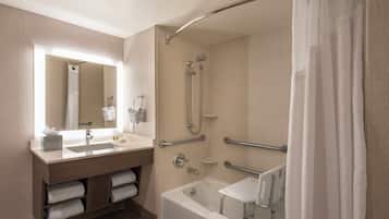 A modern bathroom with a bathtub, shower, vanity, and a mirror.