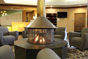 A lobby area with a central fireplace, seating arrangements, and a reception desk.
