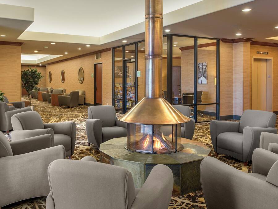 A lobby with a central fire feature, seating area, and a reception desk.
