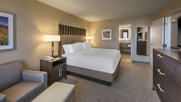 Ein Hotelzimmer mit Bett, Nachttisch, Schreibtisch, Stuhl, Kommode und Fernseher.