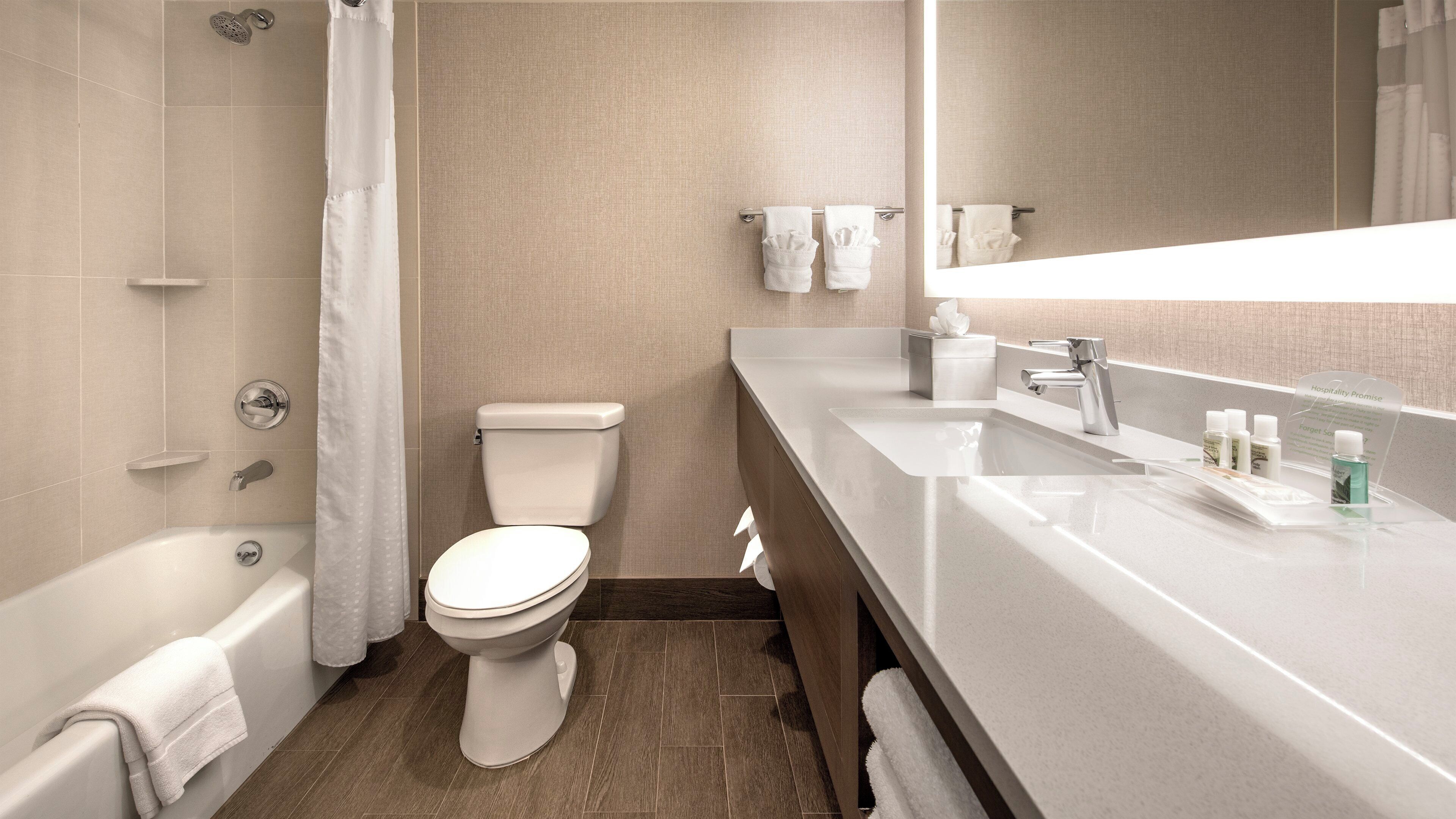 Et moderne badeværelse med badekar, toilet og vaskebord med spejl.