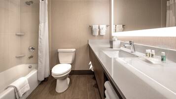 Et moderne badeværelse med badekar, toilet og vaskebord med spejl.