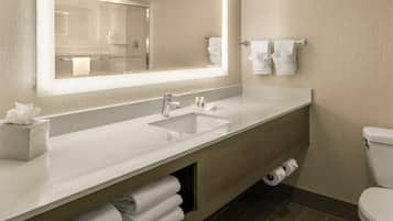 A modern bathroom with a large mirror, a sink, a toilet, and a towel rack.