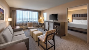A hotel room with a sofa, two chairs, a desk, a television, and a bed.