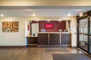 Un mostrador de recepción con una pantalla digital que muestra 'Wi-Fi gratuito en todas las habitaciones' y una cámara de seguridad sobre la puerta.