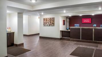 A hotel reception area with a flat-screen TV displaying 'Free Wi-Fi All Rooms' and a Dell computer.