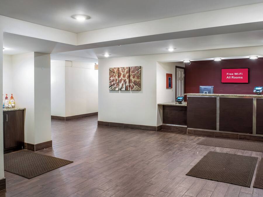 A hotel reception area with a flat-screen TV displaying 'Free Wi-Fi All Rooms' and a Dell computer.