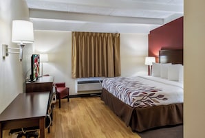 Una habitación de hotel con cama, escritorio, silla y televisor.