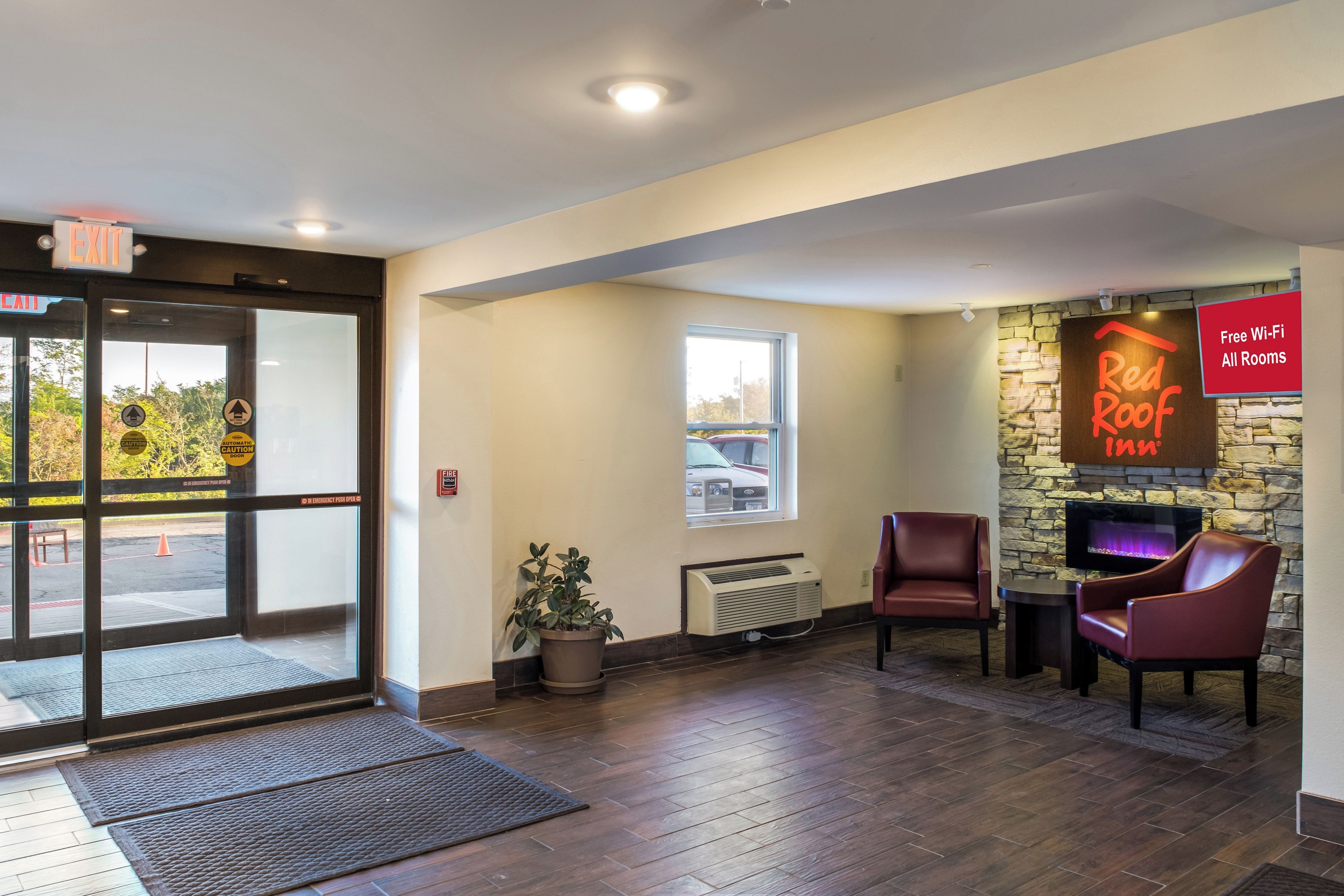 A hotel lobby with a fireplace, seating area, and a view of the parking lot.