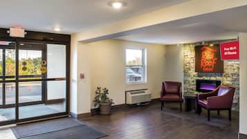 A hotel lobby with a fireplace, seating area, and a view of the parking lot.