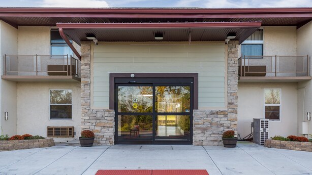A building with a stone facade, a black entrance door, and a covered entrance area. - Red Roof Inn Richmond, IN (Richmond)