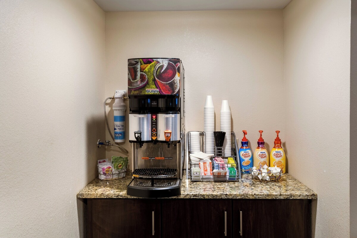 A coffee station with a Bunn coffee machine, disposable cups, and coffee creamer bottles.
