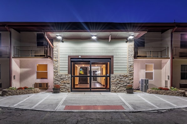 A hotel entrance with a stone facade, a covered entrance, and a ramp for accessibility.