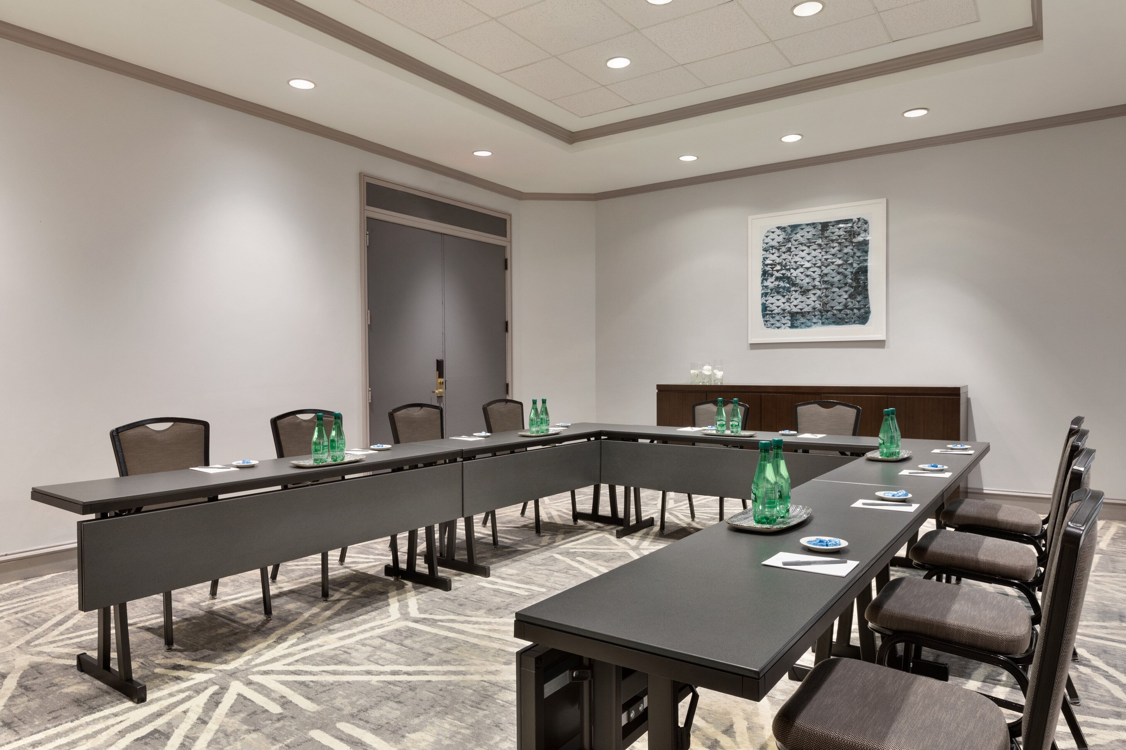 A conference room with a long table, chairs, and a patterned carpet.