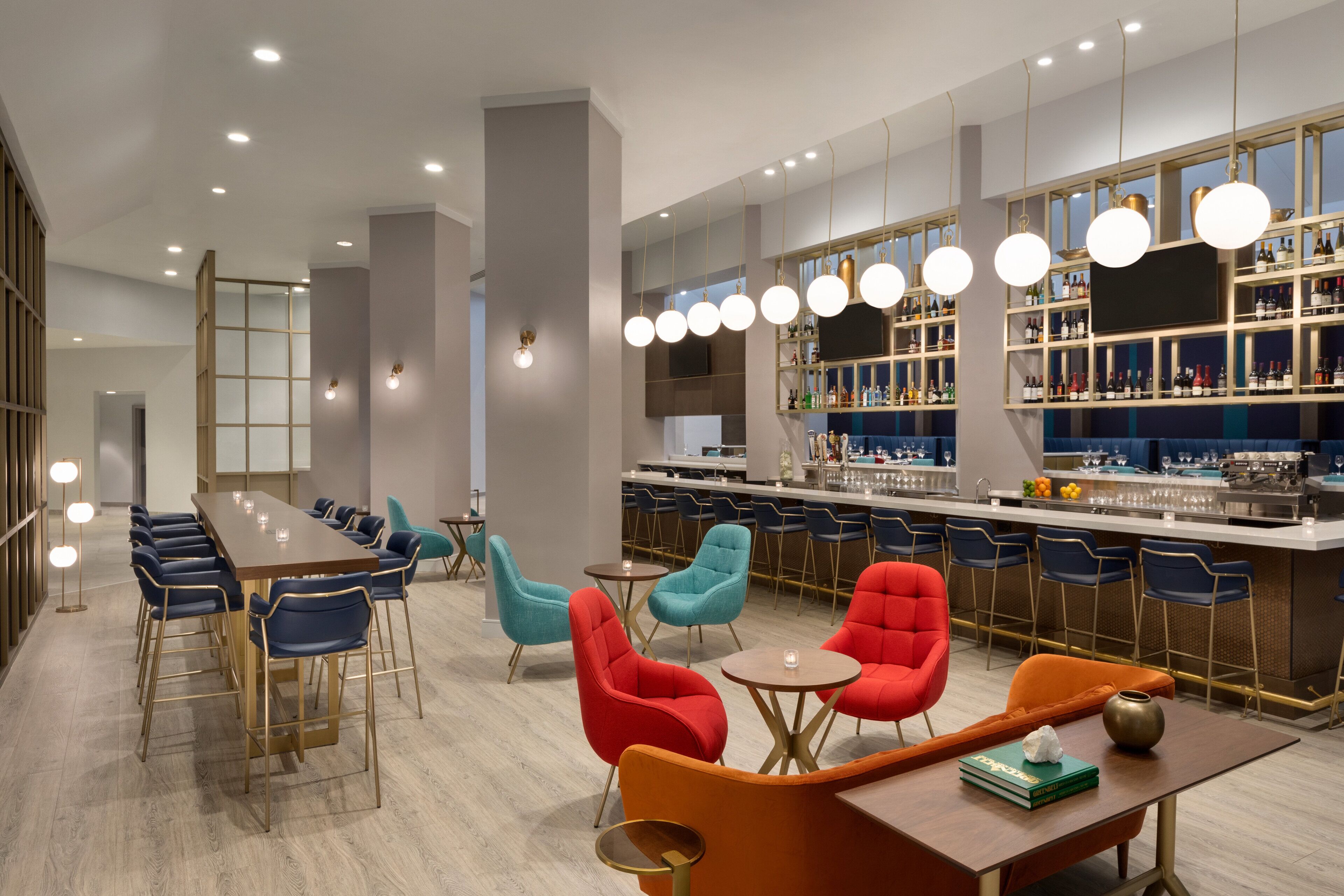 A modern bar area with a long counter, multiple seating options including bar stools and chairs, and a variety of lighting fixtures.