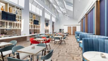 A modern restaurant with high ceilings, large windows, and a variety of seating options including tables and booths.