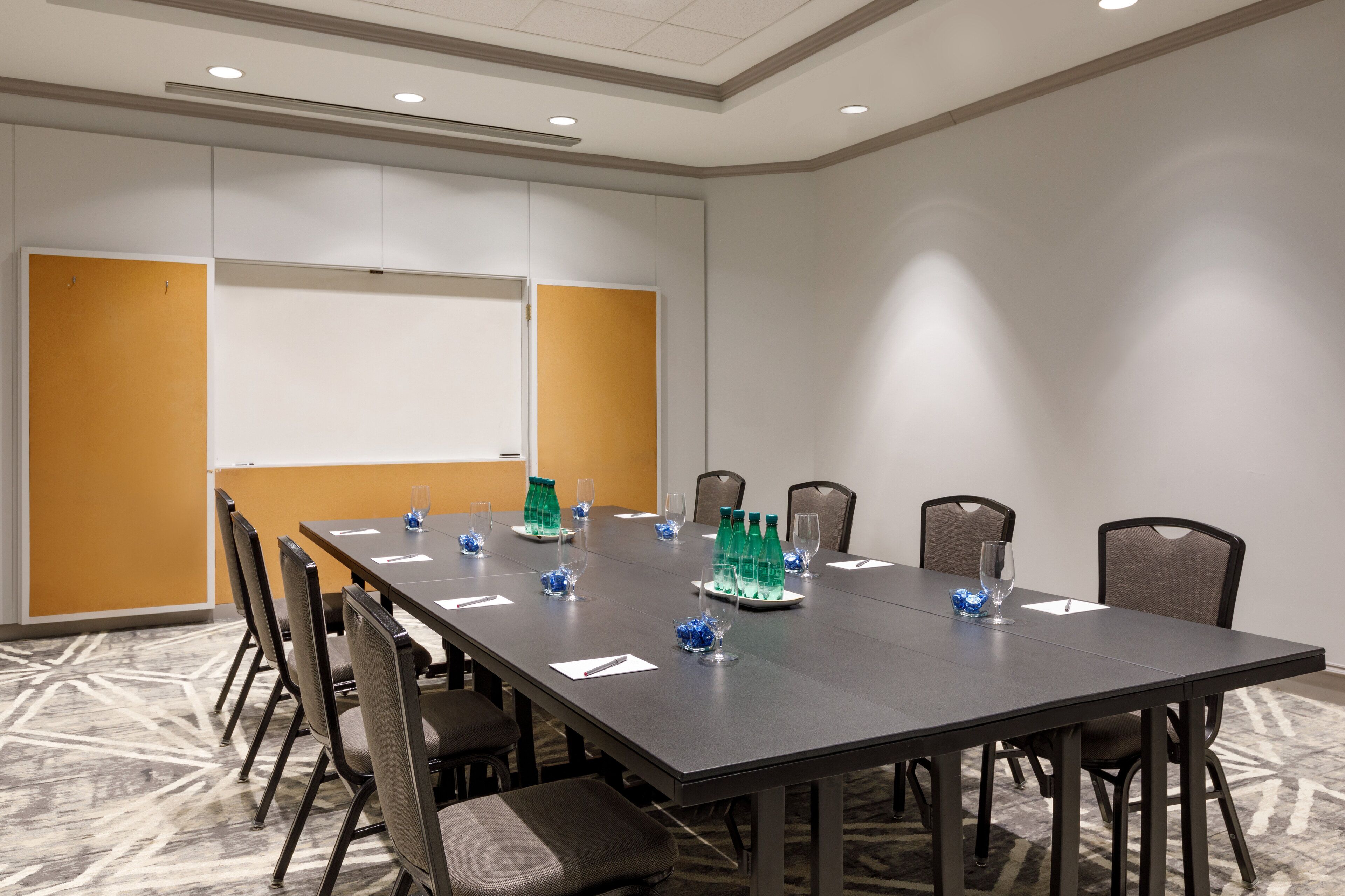 A conference room with a long table, chairs, and a whiteboard.