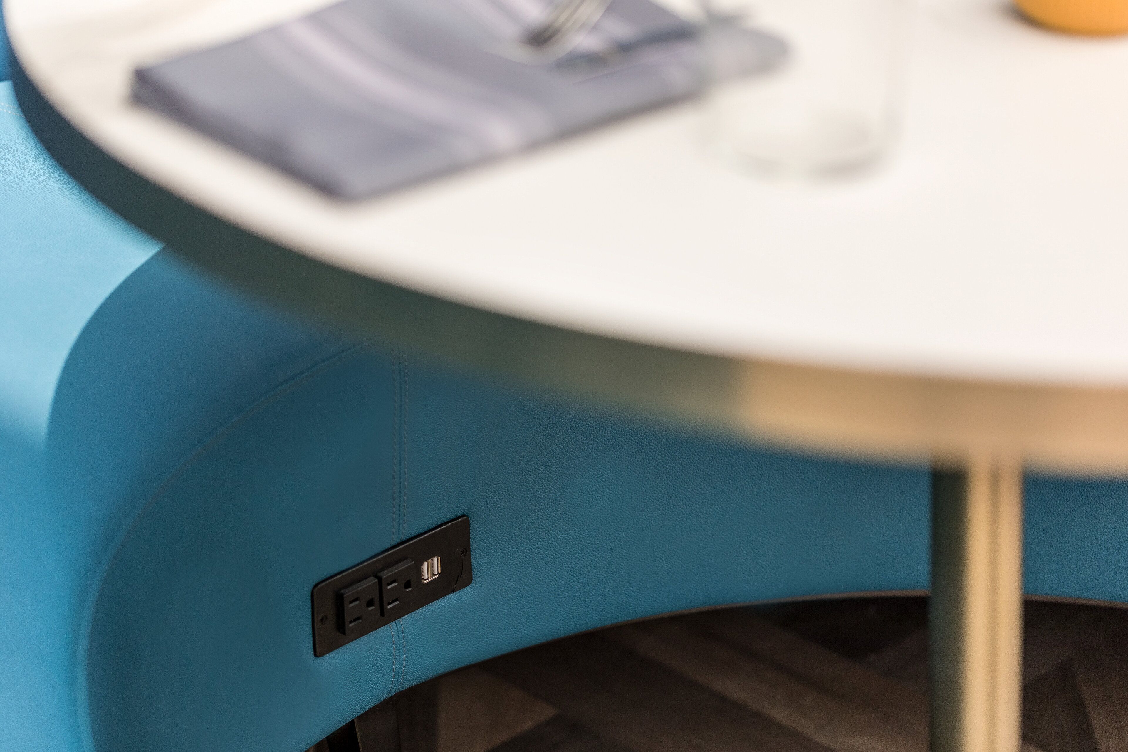A blue chair with a round table, a power outlet, and a USB port.
