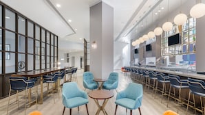 A modern bar area with a long counter, blue chairs, and a central round table.
