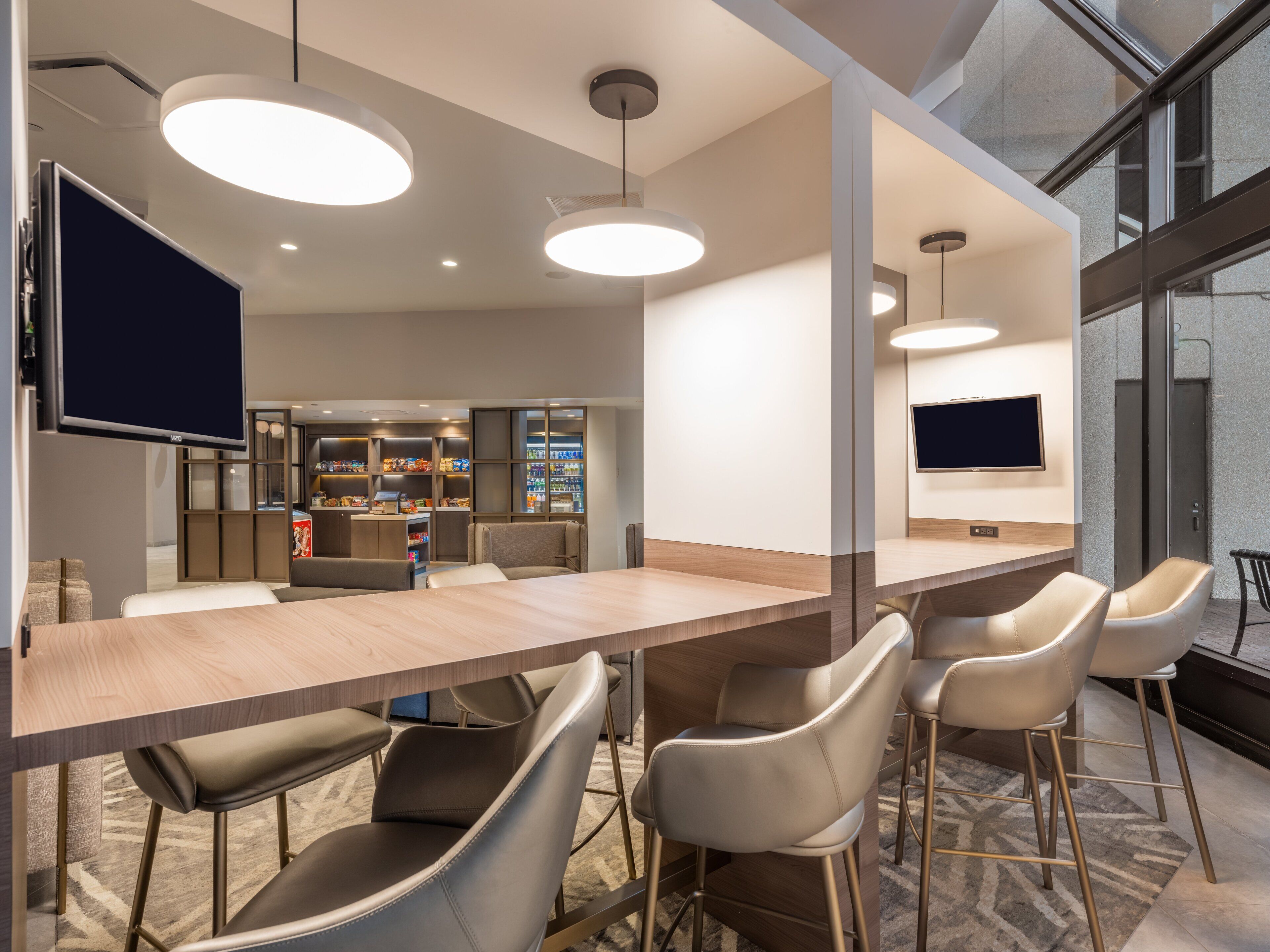 A modern bar area with a long counter, bar stools, and pendant lighting.