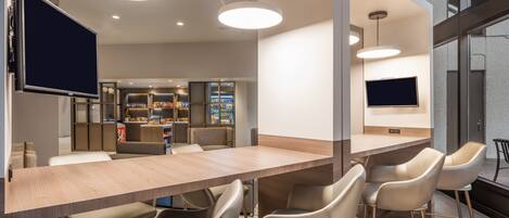 A modern bar area with a long counter, bar stools, and pendant lighting.