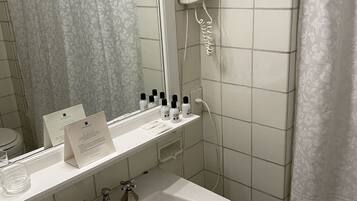 A bathroom with a white sink, mirror, and a hairdryer mounted on the wall.