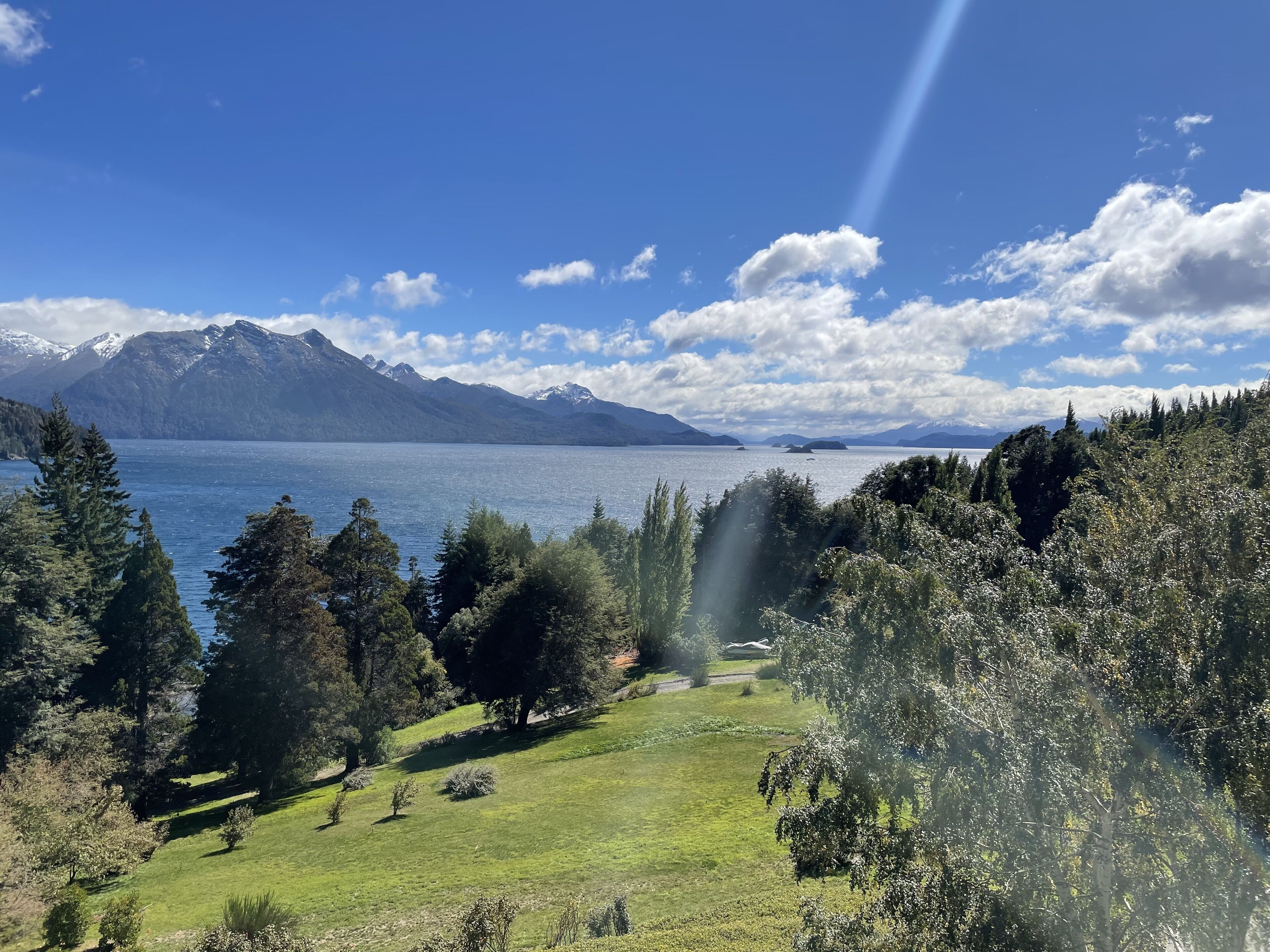 A mountainous landscape with a lake, trees, and a clear sky.